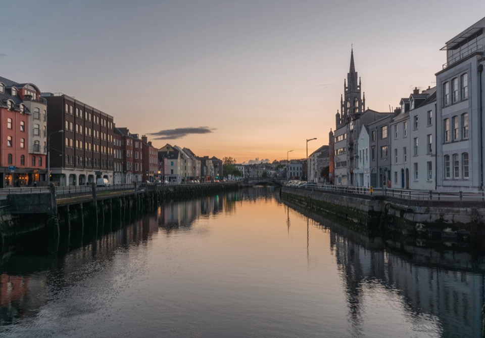 Cork city at dusk — the River Lee reflects the Georgian quays and St Fin Barre's Cathedral spire.